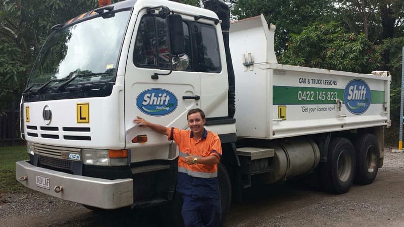 Person standing in front of a white garbage truck with green and blue branding.