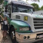 Person standing next to a green and white IVECO truck with an ‘L’ learner sign.