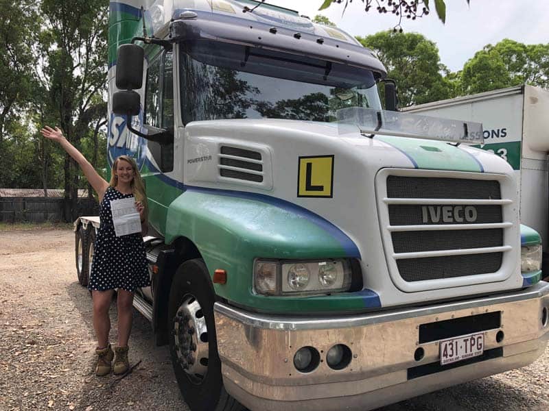 Person standing next to a green and white IVECO truck with an ‘L’ learner sign.